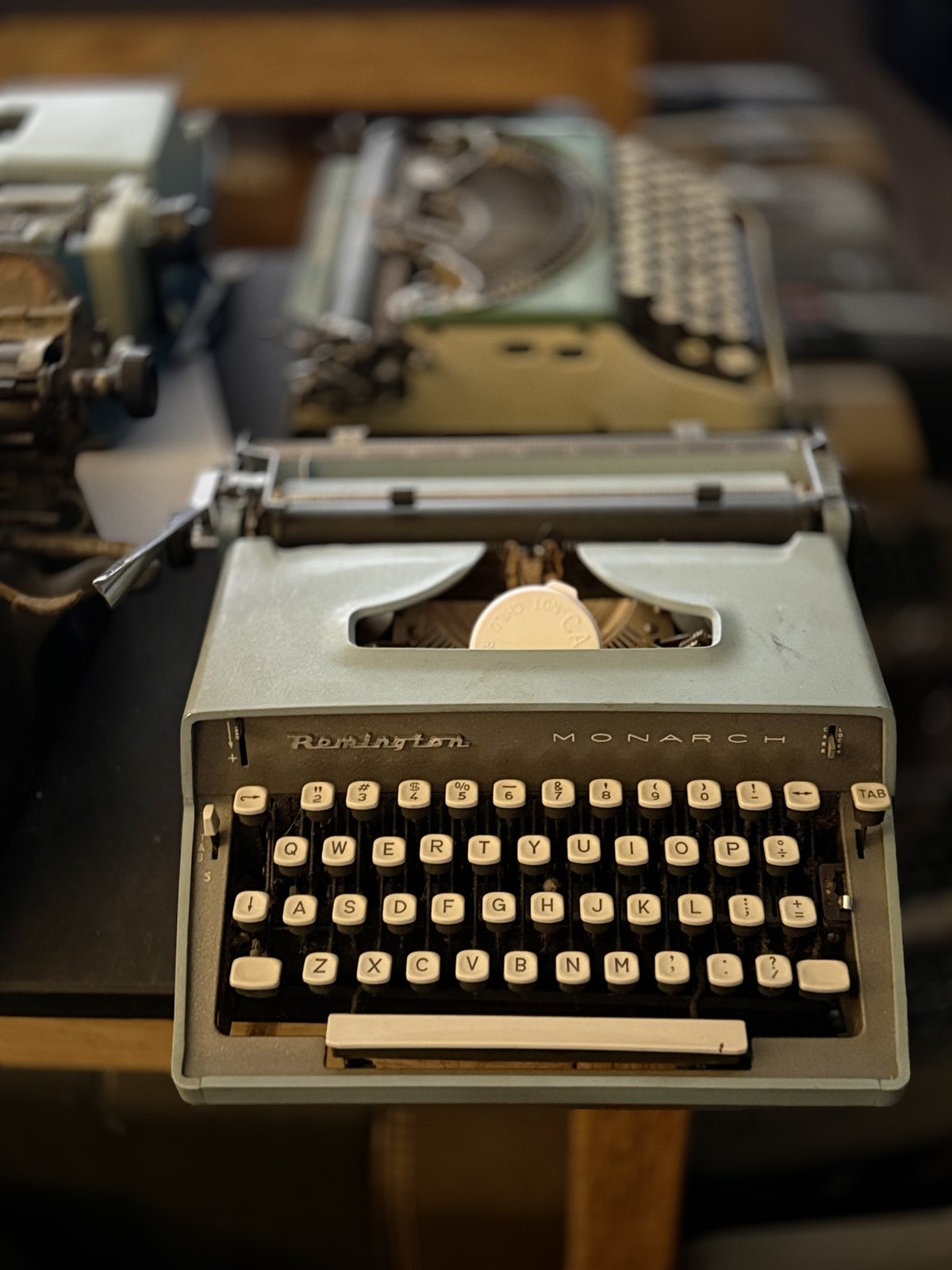 A mint-condition Remington typewriter shelved between two well-worn ones.