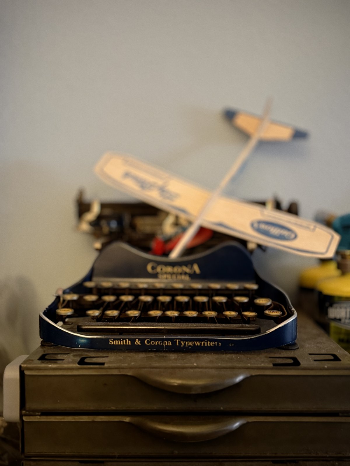 A small toy airplane parked on top of a Corona typewriter.